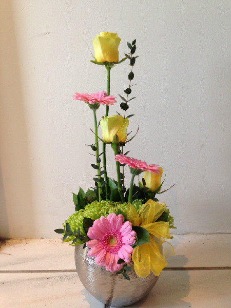 Flower arrangement including pink gerberas, yellow roses and chrysanthemums